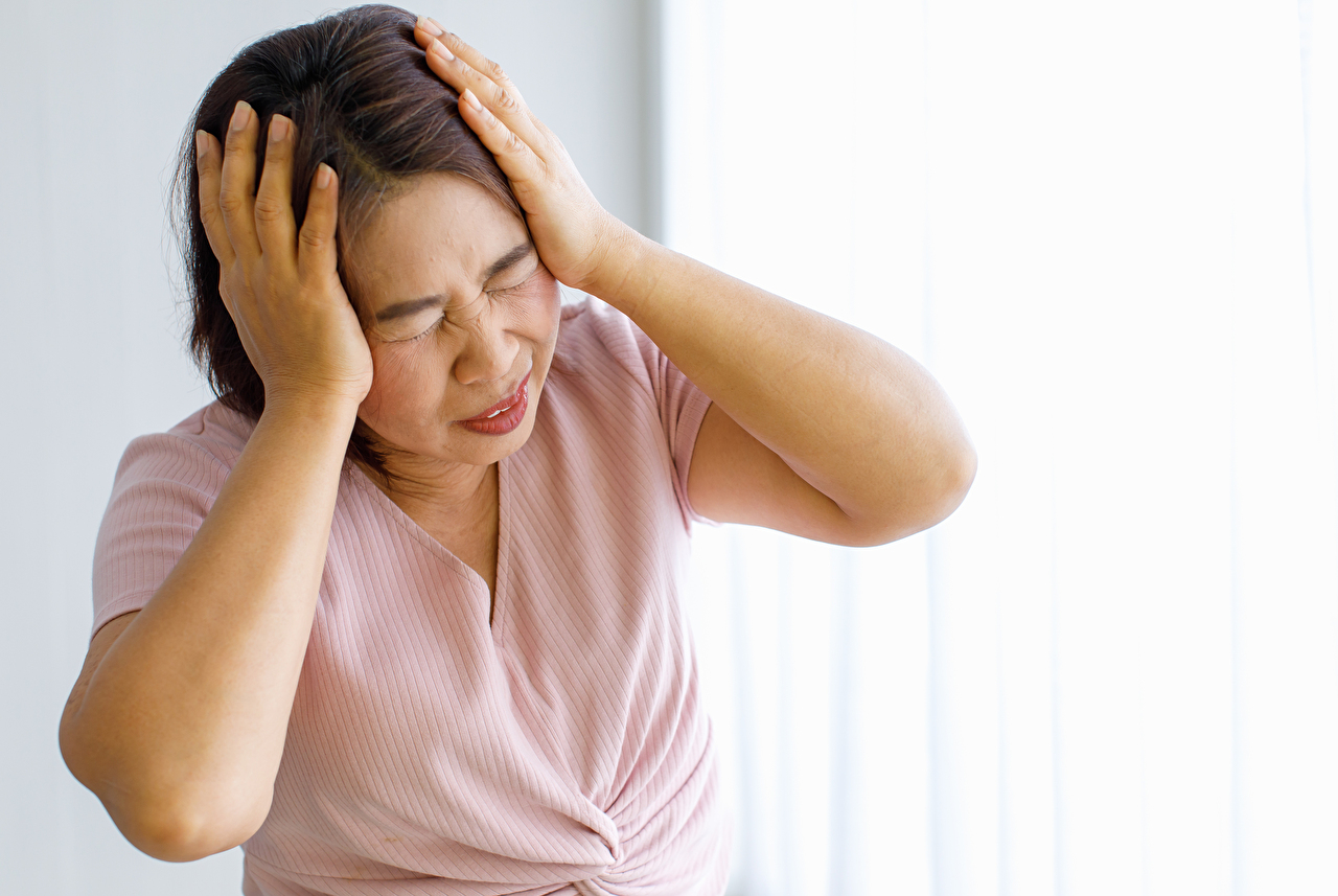 Senior woman using hands to catch and hold her head with pain and suffer warped face from headache with cerebrovascular disease or head stroke. Senior woman using hands to catch and hold her head with pain and suffer warped face from headache with cerebrovascular disease or head stroke.