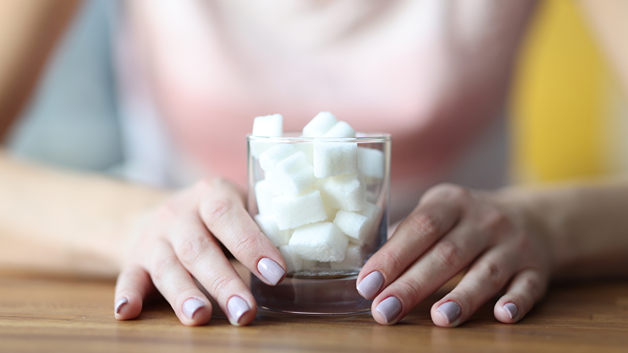 Female hands hold glass with sugar. Sugar addiction how to get rid of concept